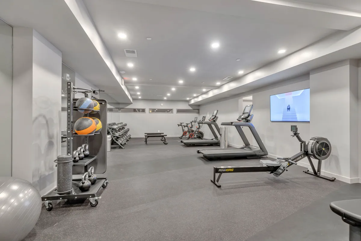 A spacious, modern gym with treadmills, stationary bikes, a rowing machine, a weights rack, and exercise balls. The room is well-lit and energetic, ideal for guests seeking to keep up with their fitness routines.