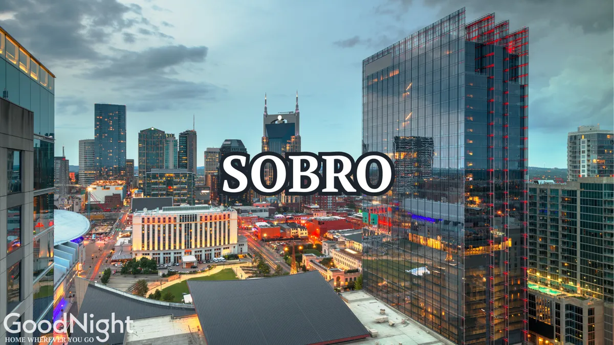 An energetic city view at dusk, with the illuminated skyline and the SOBO sign framed against the fading light. Rooftop restaurants and city lights create an inviting scene for evening adventures.