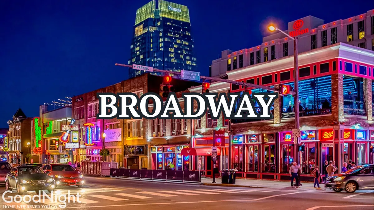 A vibrant nighttime street scene on Broadway in downtown Nashville, featuring neon lights, the iconic Broadway sign, busy sidewalks filled with people, and cars passing by. The image captures the essence of Nashville’s bustling nightlife and its legendary live music and dining venues.